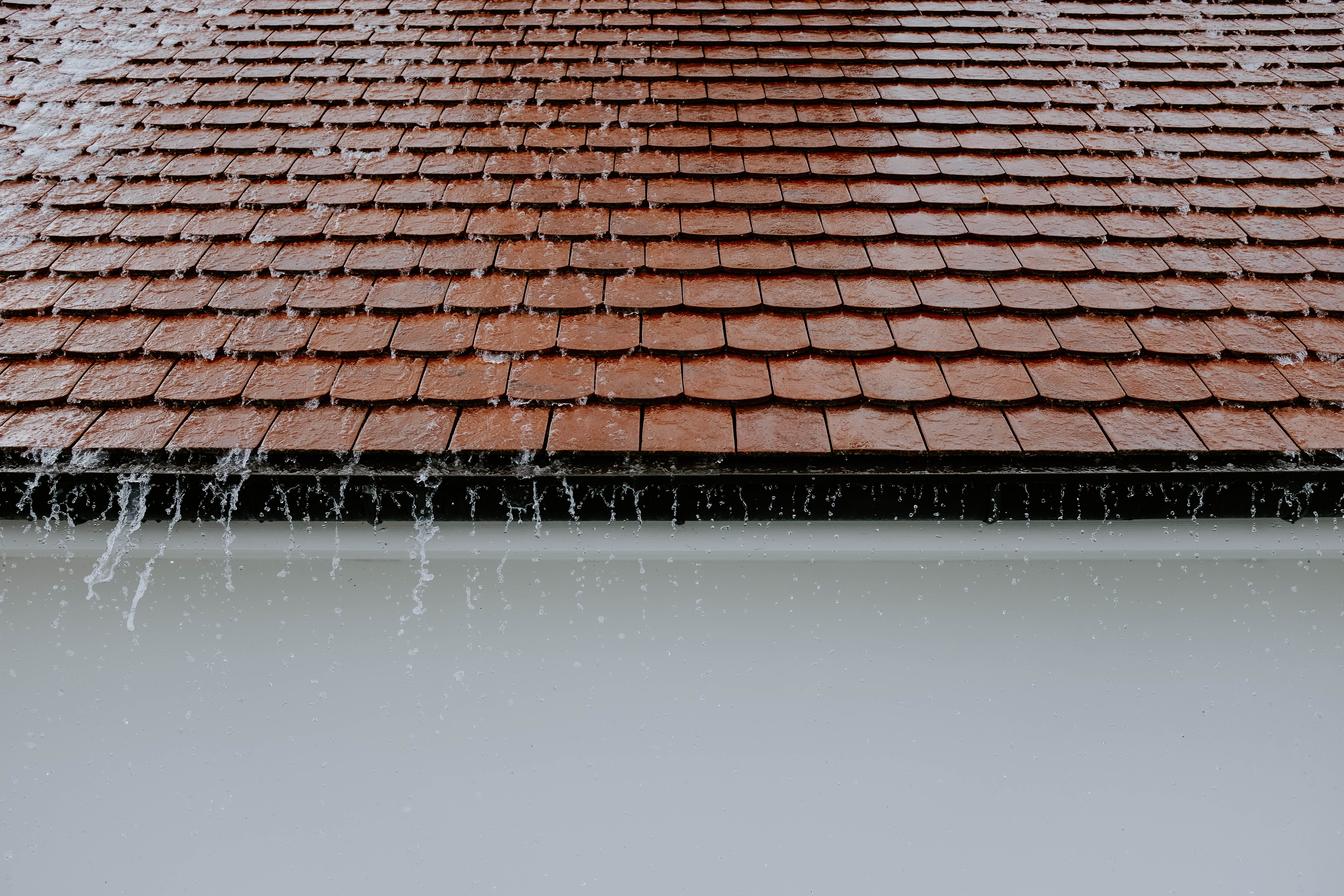 Brown roof tiles with rainwater cascading down the roof