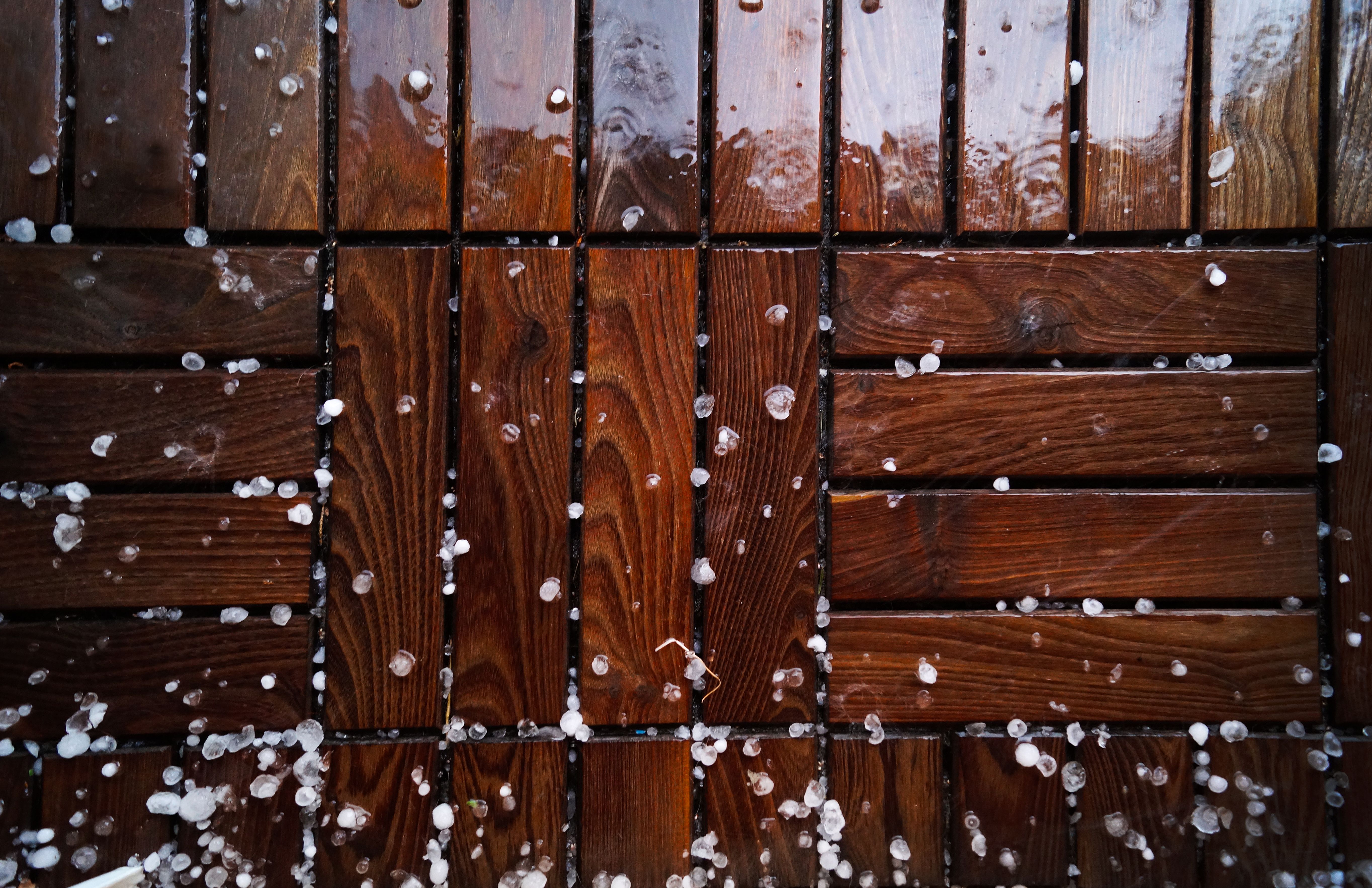 Close-up of a wet wooden deck sprinkled with sleet and snowflakes